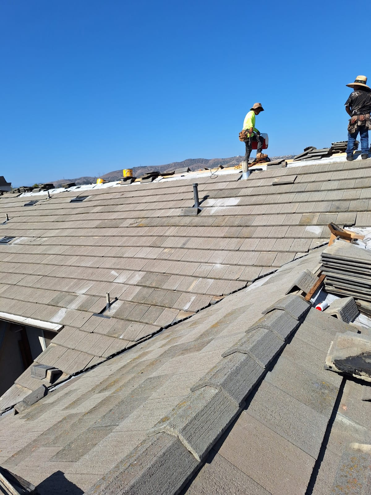 Workers on gray concrete tile roof